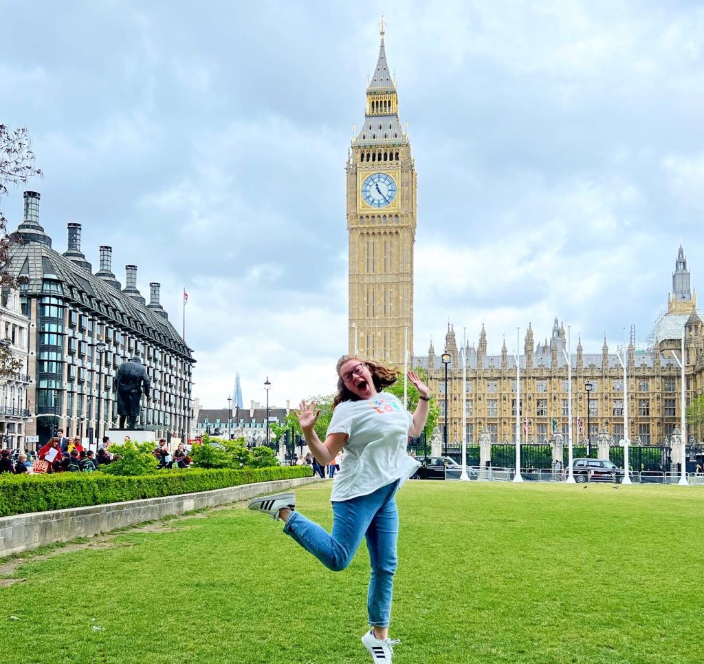 Student excitably jumping in front of Big Ben in London, England