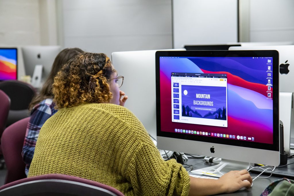 Woman working on a graphic on a Mac desktop computer
