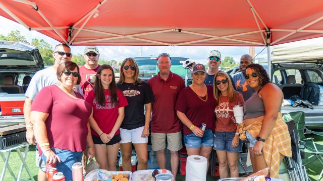 Group of 11 people under canopy at football tailgate
