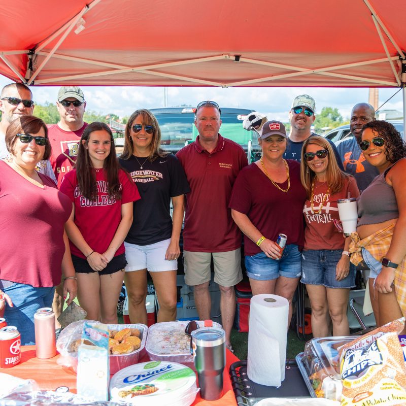 Group of 11 people under canopy at football tailgate