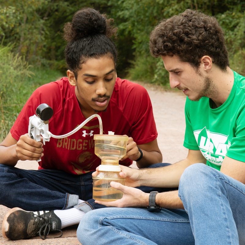 Two students using equipment for an environmental science project