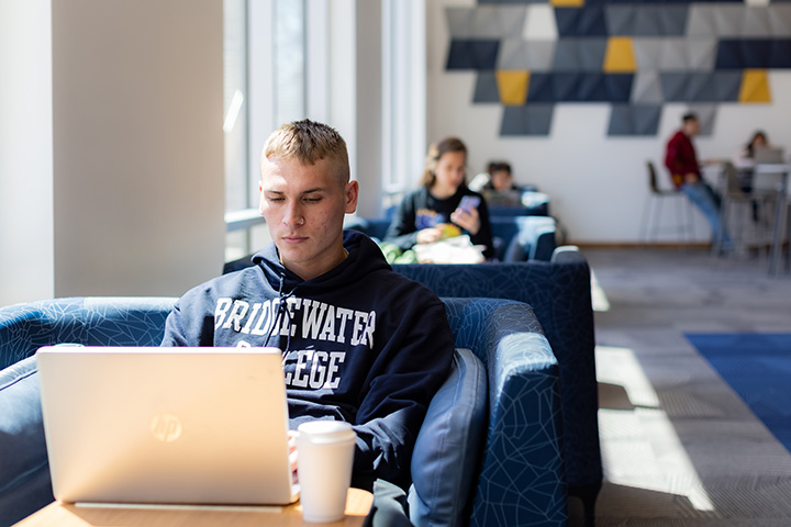 Student working with laptop sitting in front of him