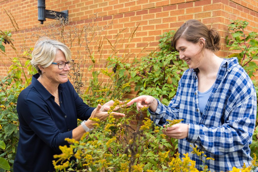 Professor looking at plant with student in the pollinator garden.