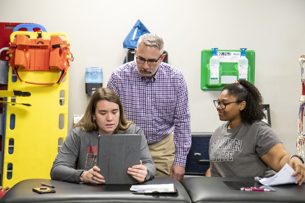 Athletic training students looking at tablet with professor