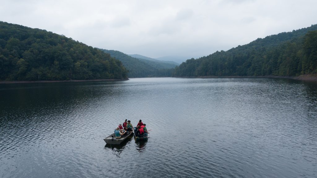 Two boats filled with students on a lake between mountains.