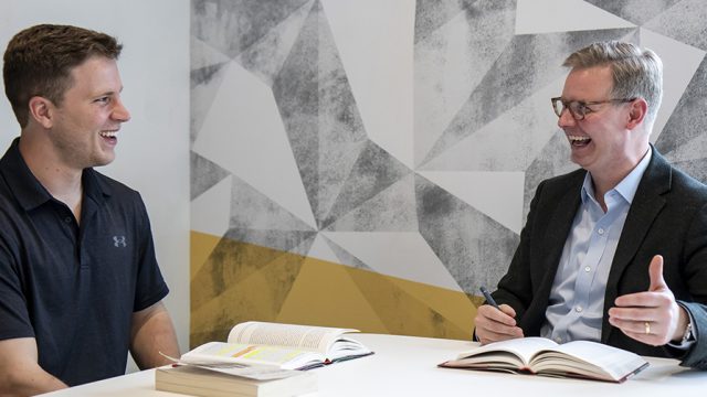 Two men sitting at a table talking and smiling