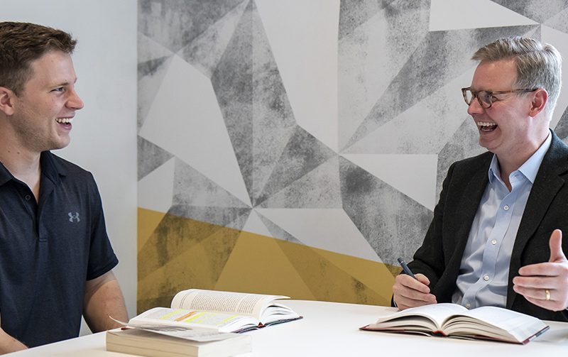 Two men sitting at a table talking and smiling