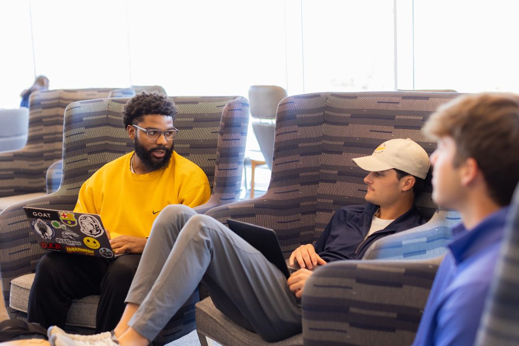 Students relaxing in chairs with laptops