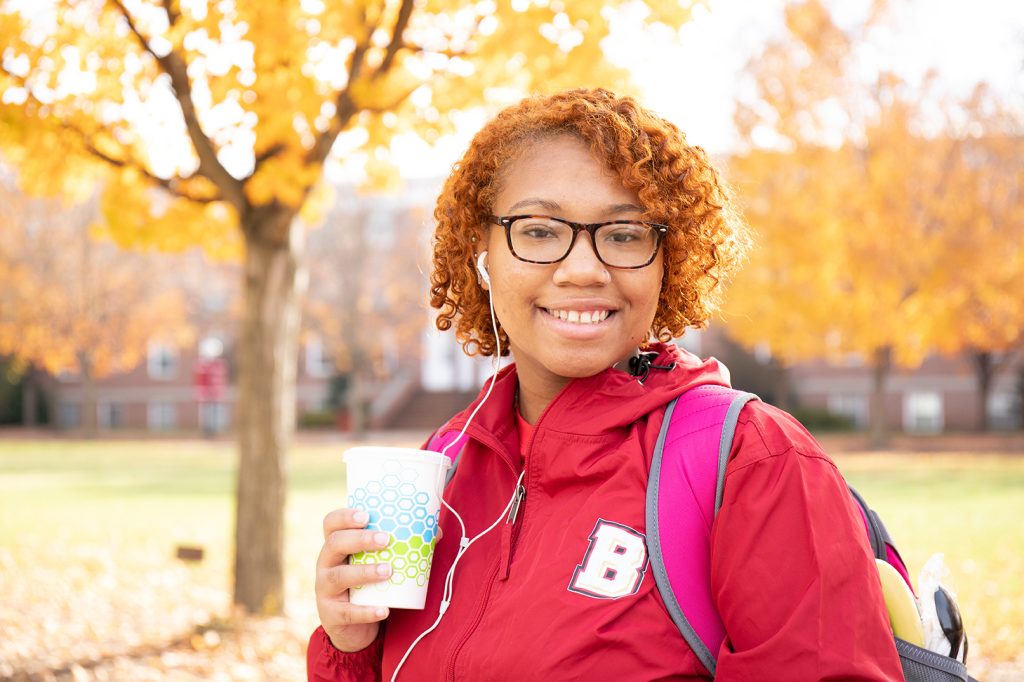 Student on the campus mall with autumn leaves