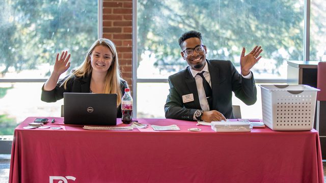 Two admissions counselors smiling and waving