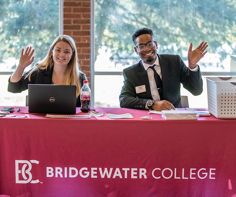 Two admissions counselors smiling and waving