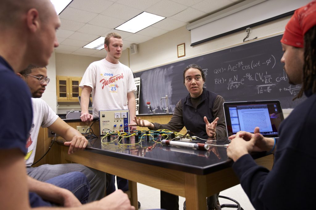 Professor sitting with students during physics class