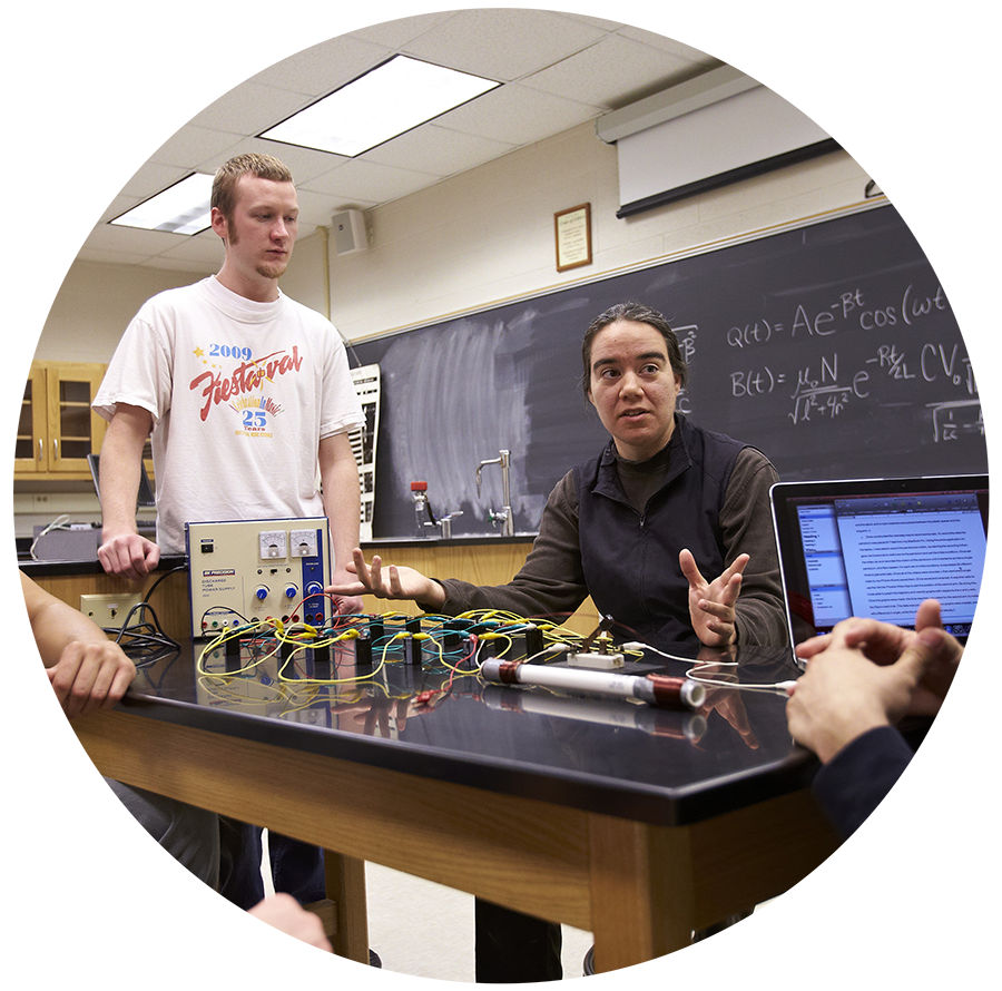 Professor sitting with students during physics class