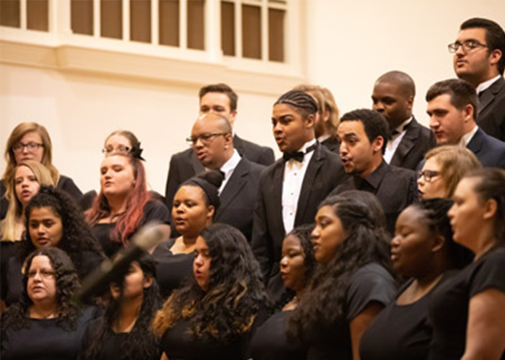 Choir members dressed in all black are pictured singing