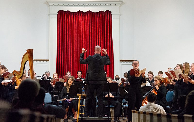 Music director standing in front large music ensemble during performance