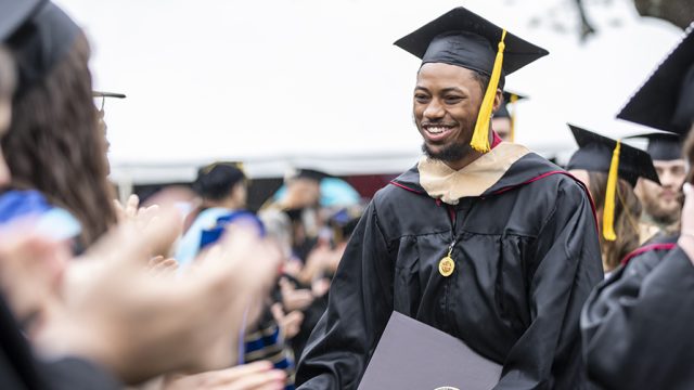 Graduate shaking people's hands walking out of Commencement