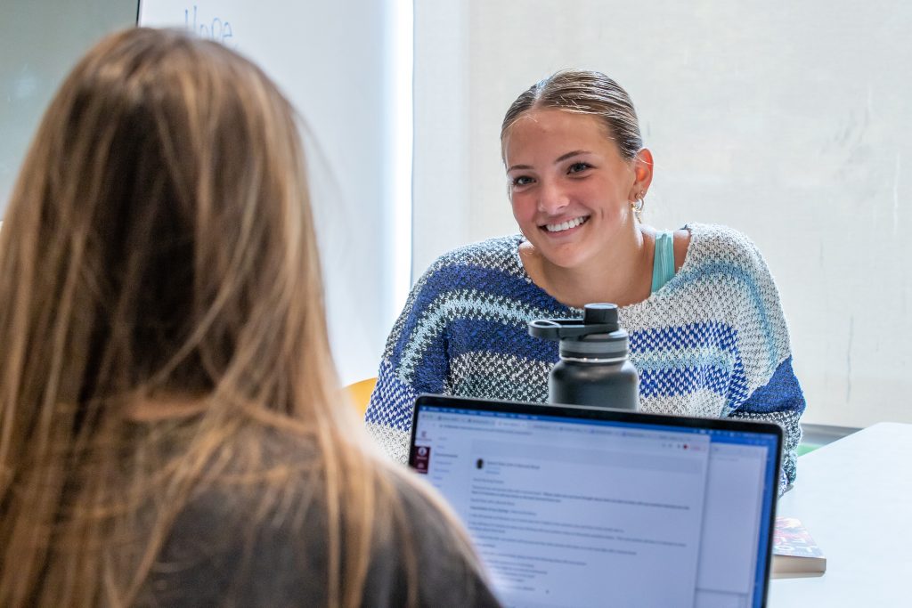 Smiling student sitting across from someone with laptop