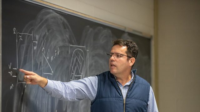 Professor Derli Amaral points to a chalkboard during a foundations of engineering class