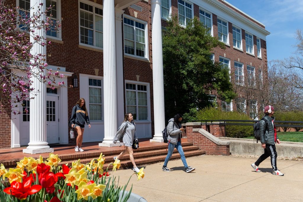 Four students walking out of Bowman Hall in the spring time