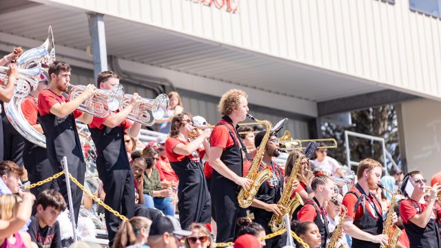 Members of the Screamin' Eagles Marching Band playing instruments in the stands at a football game