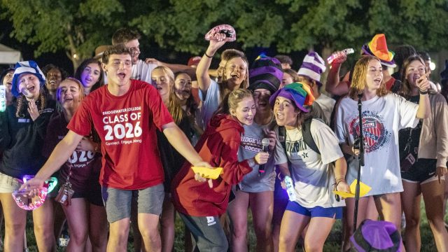 Group of students singing while wearing silly hats and holding light up tambourines