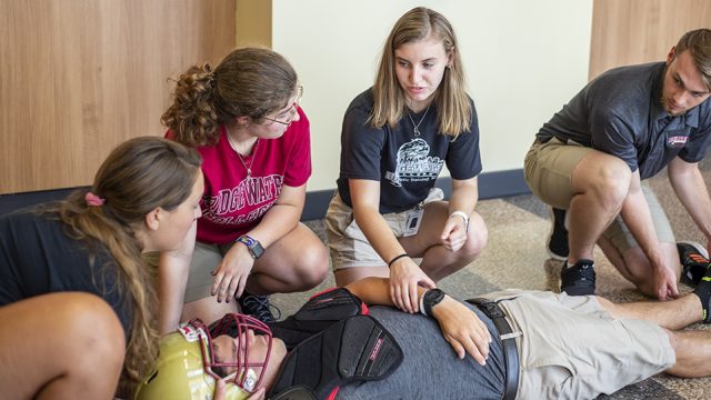 Athletic training students training for an emergency situation putting a player on a spine board