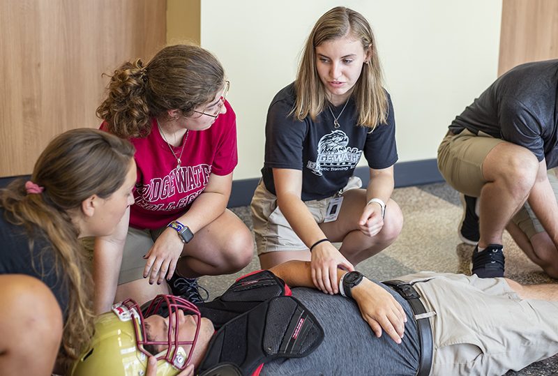 Athletic training students training for an emergency situation putting a player on a spine board