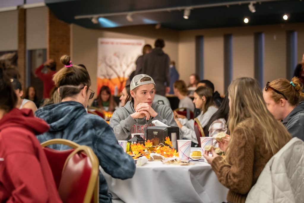 Students sitting around table eating in the dining hall