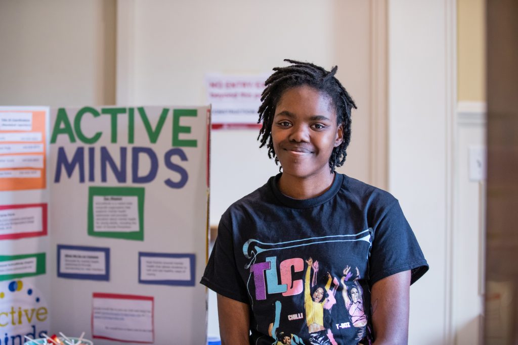 Student standing in front of information sign about the club, Active Minds