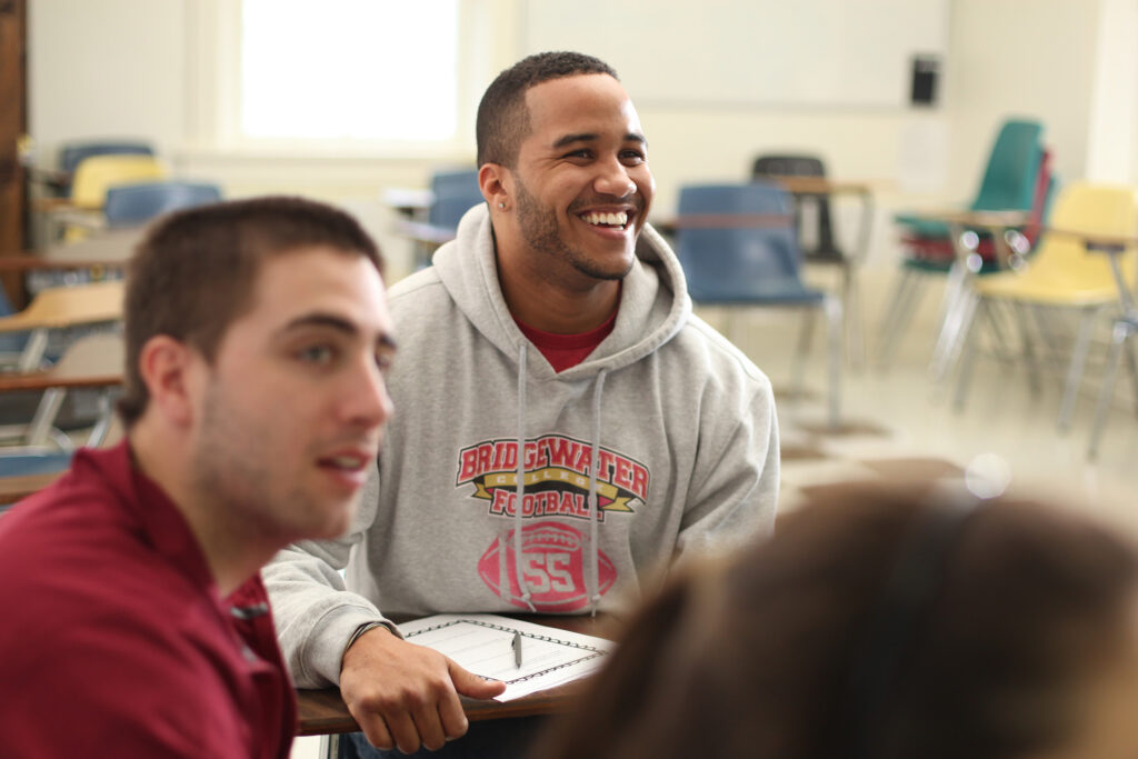 Student smiling while sitting at a desk in a classroom