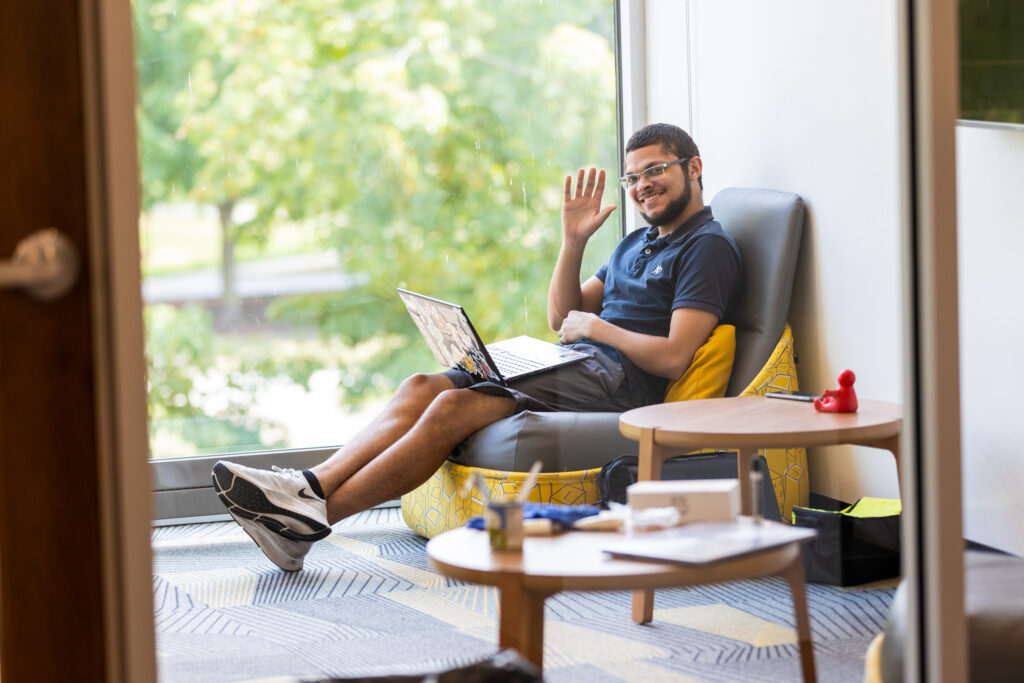 Student sitting in comfortable chair waiving at the camera