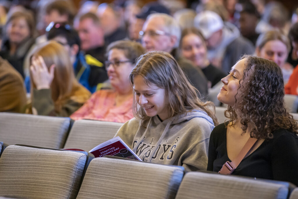 Attendees of admitted students day smiling while looking at event program