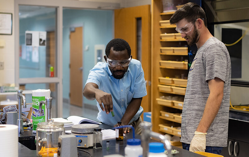 Professors using chemistry lab equipment with student