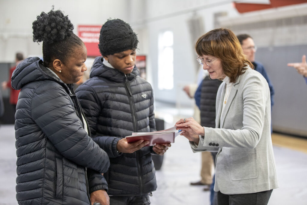 Professor helping a student and his mother during an open house