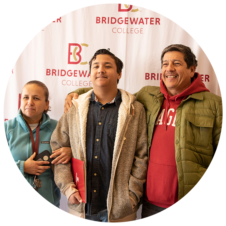 Family standing into a B-C logo printed background for a photo