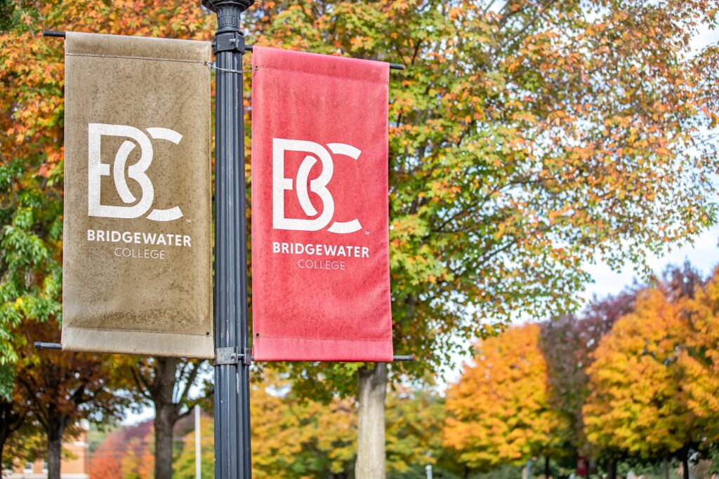 B-C flags in gold and crimson with fall trees behind them