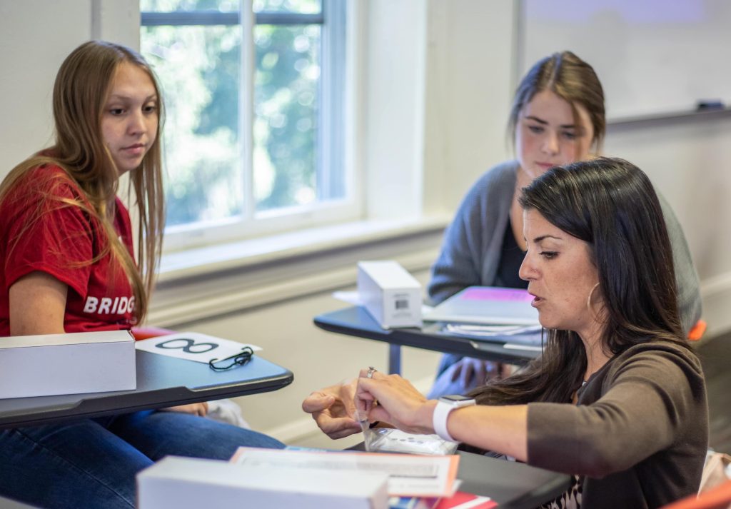 Dr. Carr opens a bag containing flashcards for two onlooking students in the Teacher Education Program.