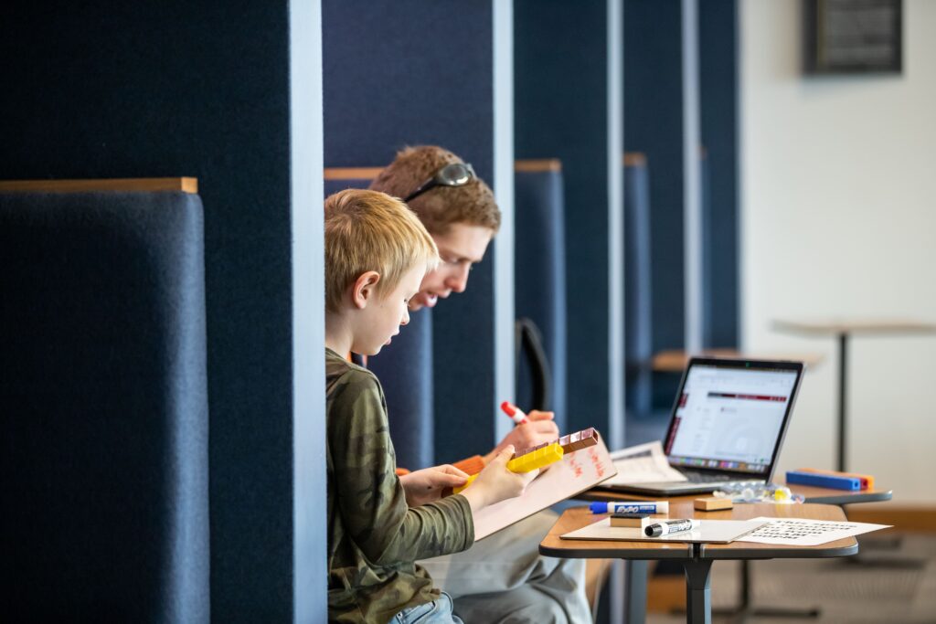 A teacher education student uses linking cubes to show a local second grade boy how to perform addition.