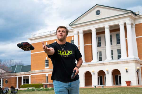 Noah Hughes throws a cornhole bag in front of McKinney Center for Science and Mathematics