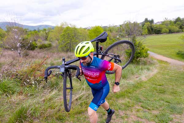 Dr. Christian Sheridan carries his bike over one shoulder