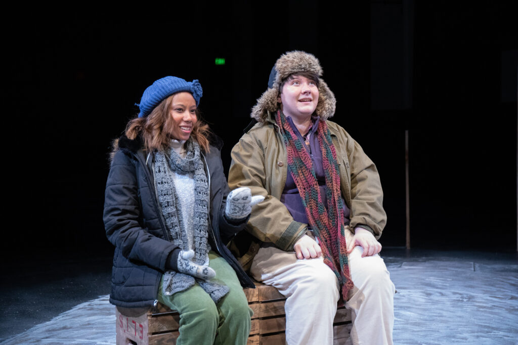 Two performers in theatre production wearing heavy winter clothes