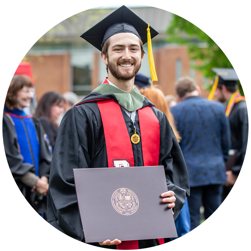 Bridgewater College graduate in cap and gown proudly holding diploma