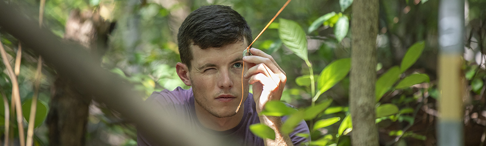 A student in the woods during a wildlife ecology class