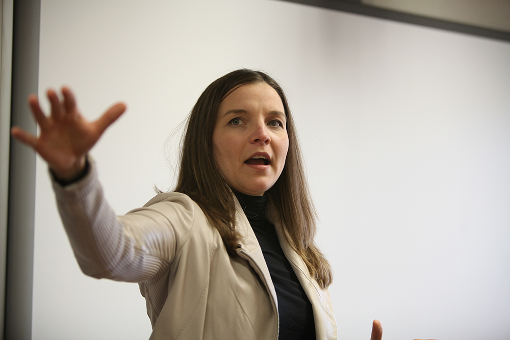 Professor speaking to a class with her hand outstretched 