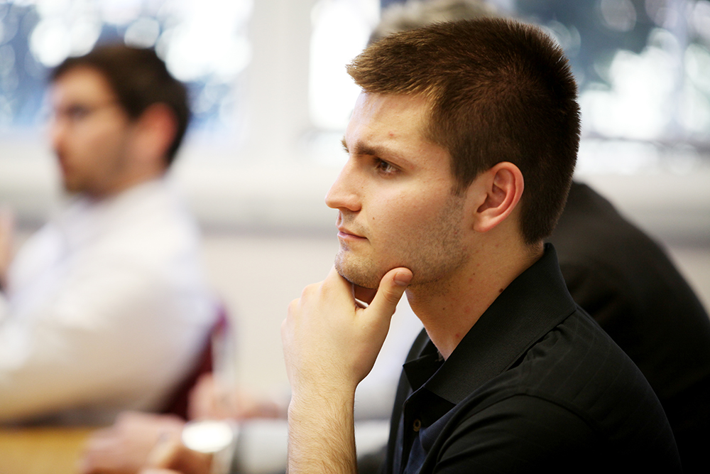 Student with hand on chin intently listening in class