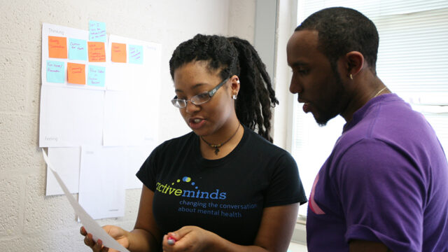 Student wearing an active minds t-shirt working with another student during class