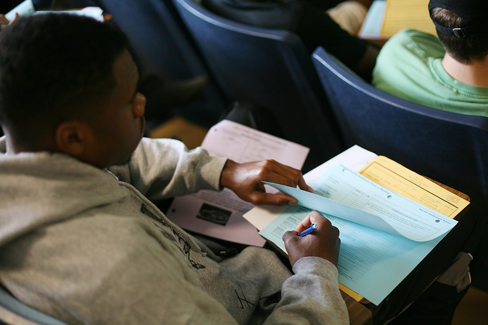 Student filling out papers sitting in a class