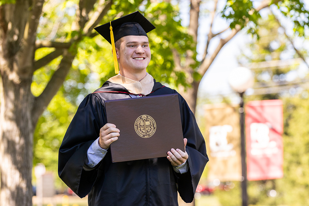 Student holding Bridgewater College diploma and smiling