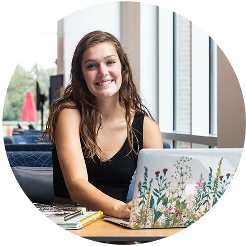 Young lady smiling sits in front of a laptop