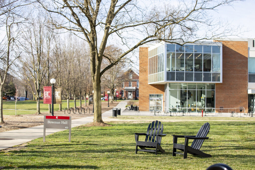 Adirondack chairs sitting on the lawn with the Forrer Learning Commons in the background 